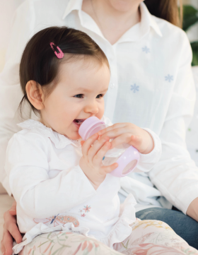 Beba sedi u majčinom krilu i pije vodu iz Elfi flašice