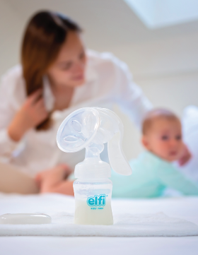 Majka i beba igraju se na krevetu pored stočića sa Elfi pumpicom za izmlazanje