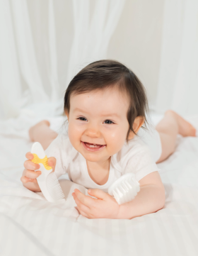 Beba leži na krevetu i igra se sa Elfi češljem i četkom