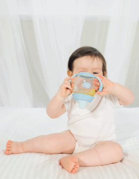 Beba u bodiću sedi na krevetu i istražuje novu Elfi flašicu sa silikonskim piskom u kojoj se nalazi sok