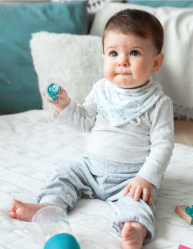 Beba sedi na krevetu i drži u ruci Elfi varalicu